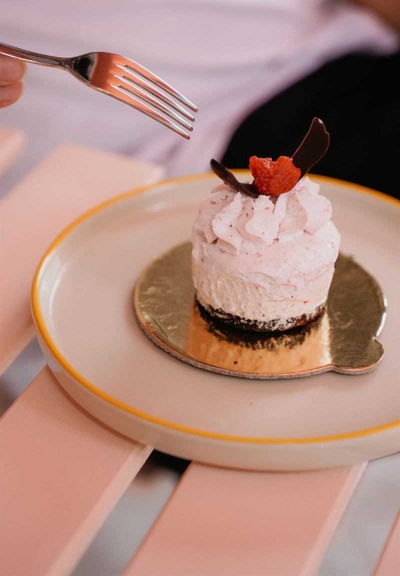 Mini cheesecake de morango com lascas de chocolate num prato, com um garfo chegando