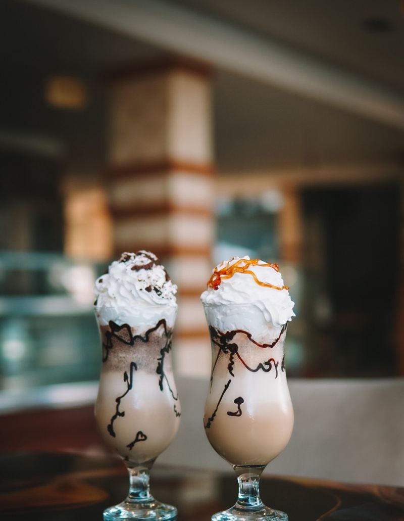 Dois milkshakes com chantili, calda de chocolate e caramelo