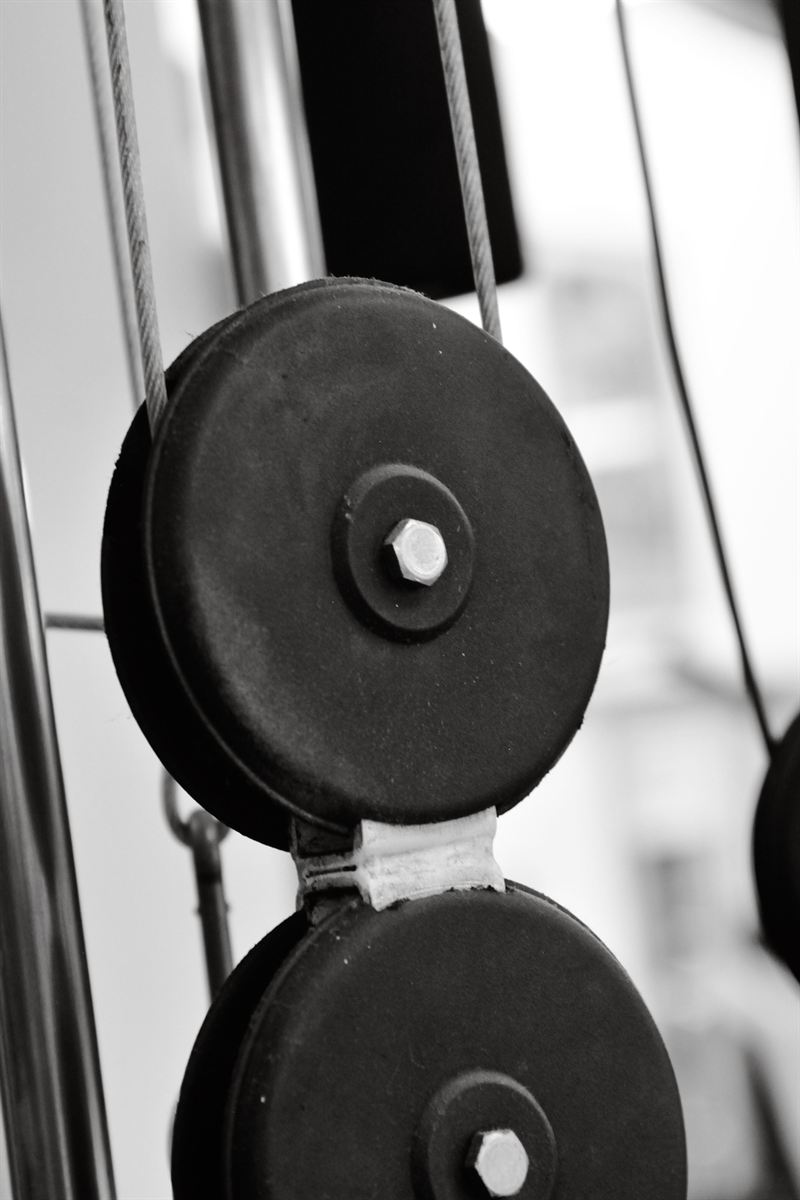 Polias pretas e cabos de aço de um aparelho de pilates, em preto e branco